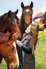 Gestuet Etzean  junge Frau wird auf der Weide von neugierigen Pferden umringt