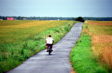 Polen  Junge auf Moped in Landschaft