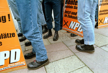 Beine und Stiefel von Skinheads mit NPD-Plakaten