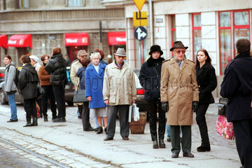 Menschen warten an einer Strassenbahnhaltestelle in Posen  Polen