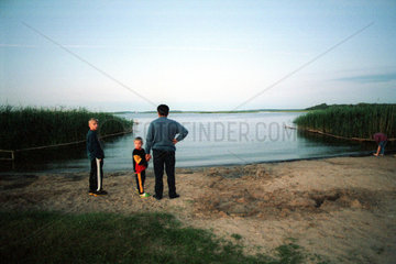Vater mit seinen Soehnen an einem See in den Masuren  Polen