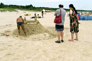 Swinemuende  Polen  ein Mann hat eine Sandburg am Strand gebaut