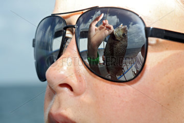 St. Pete Beach  USA  selbst geangelter Fisch spiegelt sich in der Sonnenbrille eines Jungen