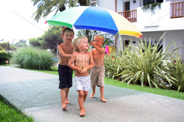 Valldemossa  Kinder laufen bei Regen unter einem Sonnenschirm