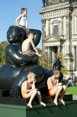 Berlin  Deutschland  Jungen sitzen auf einer Bronzeskulptur von Fernando Botero im Berliner Lustgarten