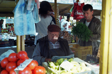 Verkaeufer liest Zeitung auf einem Obst- und Gemuesemarkt in Plovdiv  Bulgarien