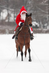 Hoppegarten  Deutschland  Weihnachtsmann reitet auf einem Pferd durch den Schnee