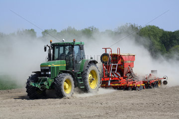 Traktor auf trockenem Feld wirbelt Staub auf