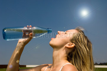 Junge Frau tringt Wasser aus einer Flasche  Berlin