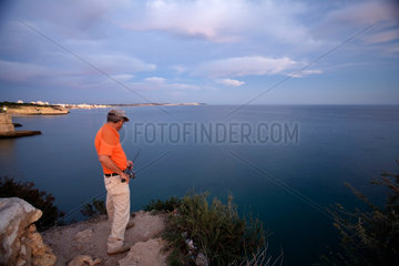 Porches  Lagoa  Portugal  ein Mann angelt an der Kueste