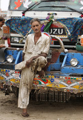 Karatschi  Pakistan  ein Automechaniker lehnt sich an einen LKW