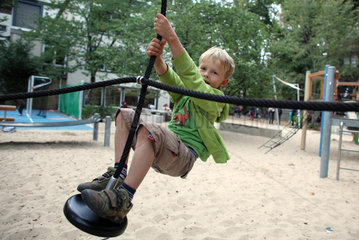Berlin  Deutschland  Junge faehrt mit einer Seilbahn auf einem Kinderspielplatz