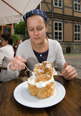 Goslar  Deutschland  Eine Frau isst Riesenwindbeutel mit Sahne und Kirschen