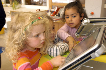 Kinder verschiedener Nationalitaeten lernen an einem Computer