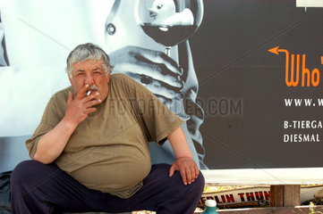 Berlin  ein alter auslaendischer Mann beim Rauchen am Potsdamer Platz