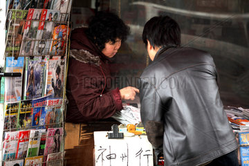 Shanghai  Mann und Verkaeuferin an einem Zeitungskiosk