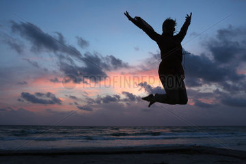 Pass A Grille  Vereinigte Staaten von Amerika  Silhouette  Frau macht einen Luftsprung bei Daemmerung am Strand