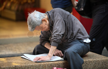 Macau  China  Mann liest eine Tageszeitung