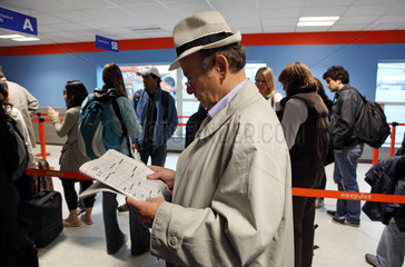 Luton  Grossbritannien  Reisender wartet Zeitung lesend auf die Abfertigung