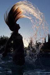 Torre Alfina  Italien  Silhouette  Maedchen wirft im Swimmingpool ihr nasses Haar zurueck