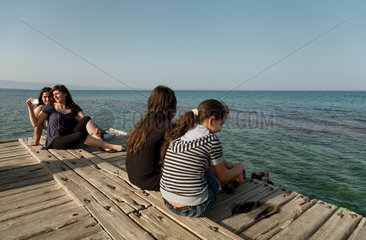 Famagusta  Tuerkische Republik Nordzypern  Maedchen sitzen auf einem Steg am Mittelmeer