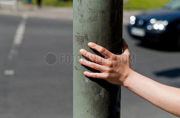 Berlin  Deutschland  Frau stuetzt sich mit ihrer Hand an einem Laternenpfahl ab