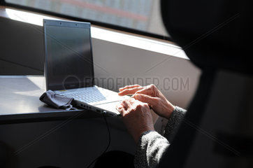 Berlin  Deutschland  eine Frau bedient ein Laptop waehrend einer Zugfahrt