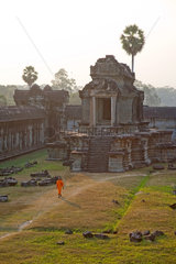 Angkor  Kambodscha  ein Moench laeuft vor einer der Bibliotheken im Hof