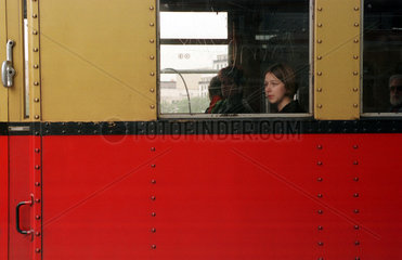 Junge Frau sitzt in S-Bahn  schaut vertraeumt aus Fenster