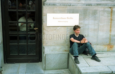 Berlin  junger Mann sitzt wartend am Buehneneingang des Konzerthaus Berlin