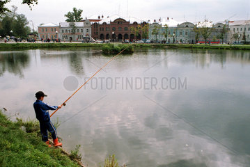 Junge angelt im Teich inmitten der Stadt