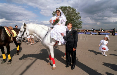 Hochzeitspaar  Braut sitzt auf einem weissem Pferd