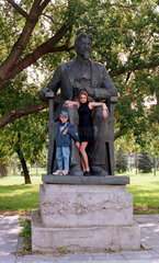 Junges Maedchen mit ihrem Bruder vor einer Statue