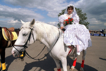 Braut sitzt auf einem weissem Pferd