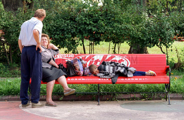 Junge schlaeft auf einer Parkbank