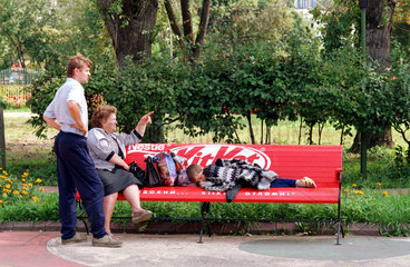 Junge schlaeft auf einer Parkbank