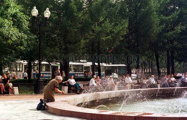 Moskau  alte Frau an einem Brunnen in einer Parkanlage