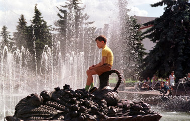 Moskau  Junge sitzt auf einer Plastik in einer Brunnenanlage
