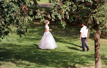 Moskau  junge Braut im Hochzeitskleid erholt sich in einer Gruenanlage