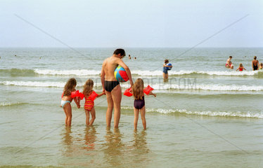 Borkum  am Strand  Mann und drei Kinder wollen sich ins Wasser wagen