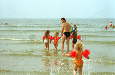 Borkum  am Strand  Mann und vier Kinder wollen sich ins Wasser wagen