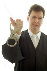 Anwalt haelt Handschellen mit dem Zeigefinger hoch