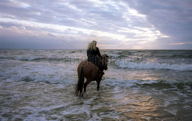Miedzyzdroje  eine junge blonde Frau reitet in den Sonnenuntergang