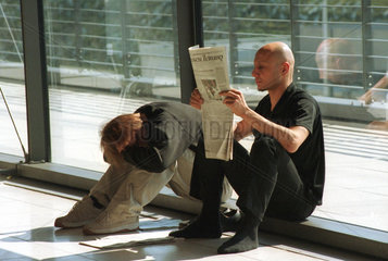 CeBIT 2001  Messebesucher lesen in einer Ruhepause eine Zeitung  Hannover  Deutschland