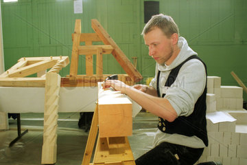 Berlin  Zimmermanngeselle bearbeitet einen Holzbalken