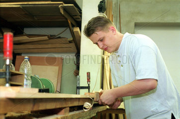 Berlin  ein Umschueler (Bootsbauer) bearbeitet eine Holzplanke