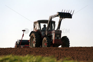 Ein Landwirt pfluegt mit einem Traktor sein Feld in Schoenhagen  Deutschland