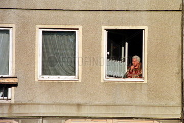Ein Mann raucht eine Zigarette am offenen Fenster  Berlin  Deutschland
