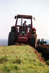 Ein Landwirt pfluegt mit einem Traktor sein Feld in Schoenhagen  Deutschland