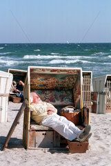Ein Mann liegt in einem Strandkorb und geniesst die Herbstsonne  Damp 2000  Deutschland